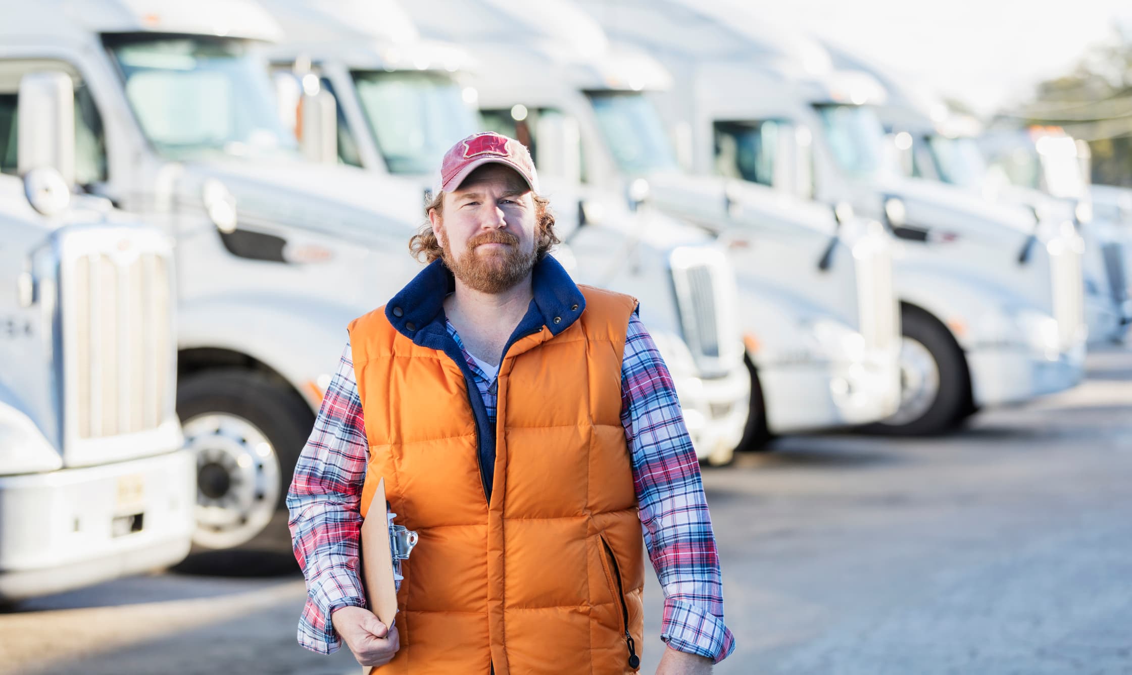 Commercial fleet manager standing in front of parked trucks